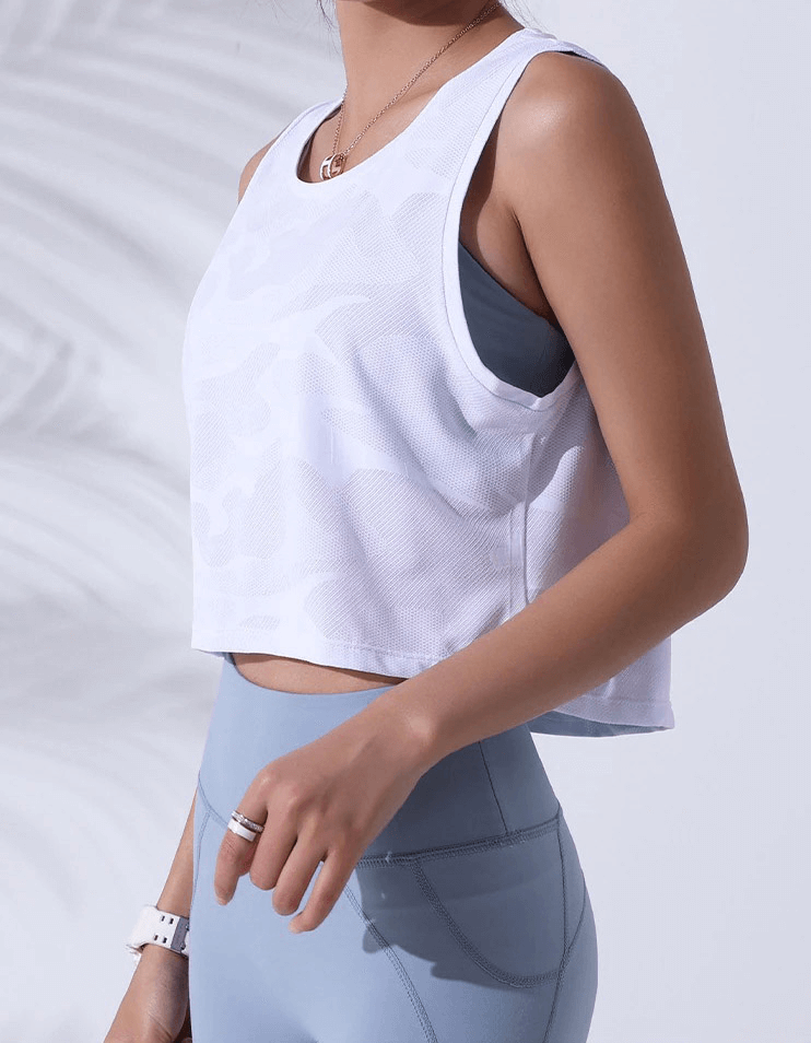 Woman wearing a breathable white camouflage running tank and blue leggings, perfect for fitness and yoga workouts.